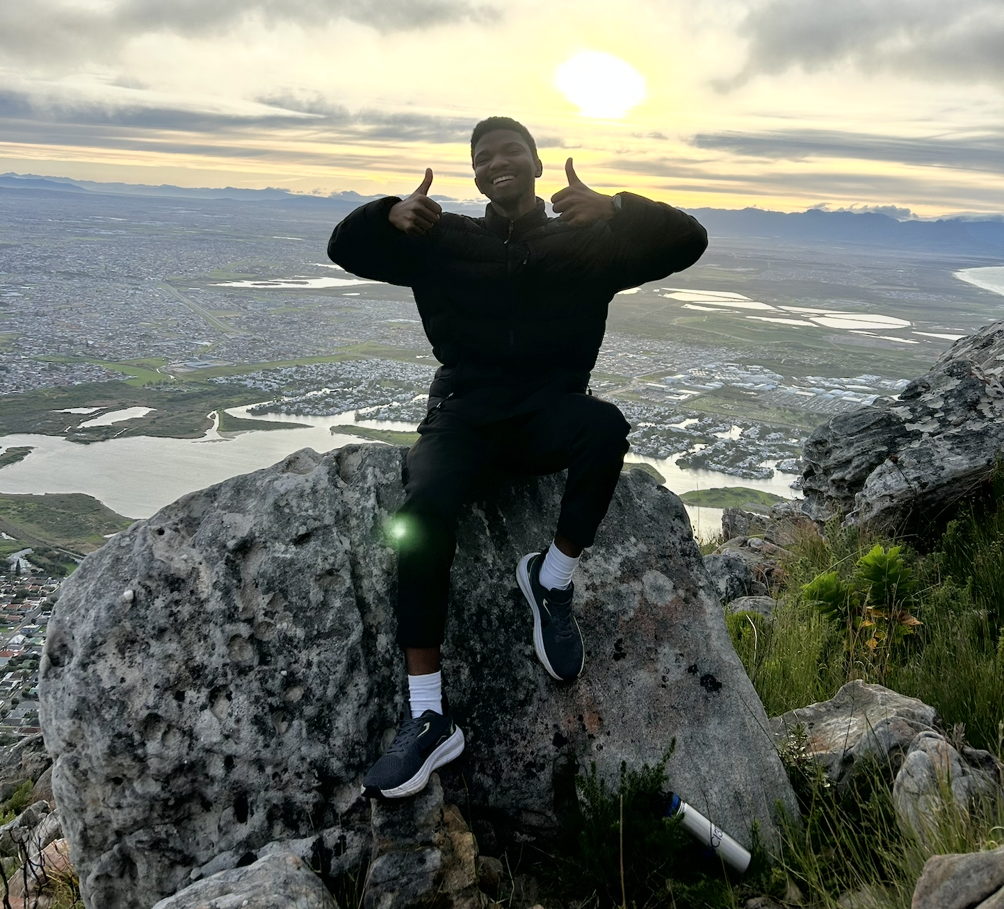 Joshua Salako sitting on a mountain at sunrise